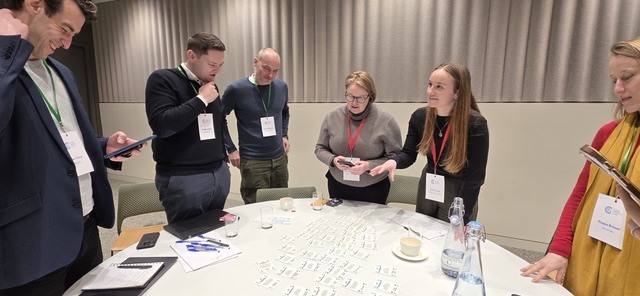 Workshop attendees gathered around a table sorting AI use-case cards